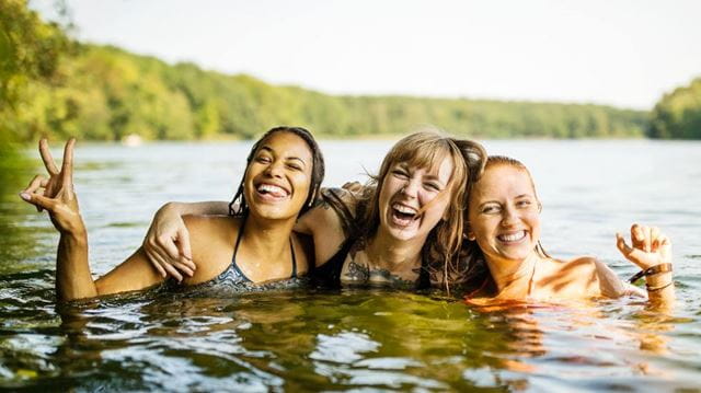 Wild swimming women smiling lake
